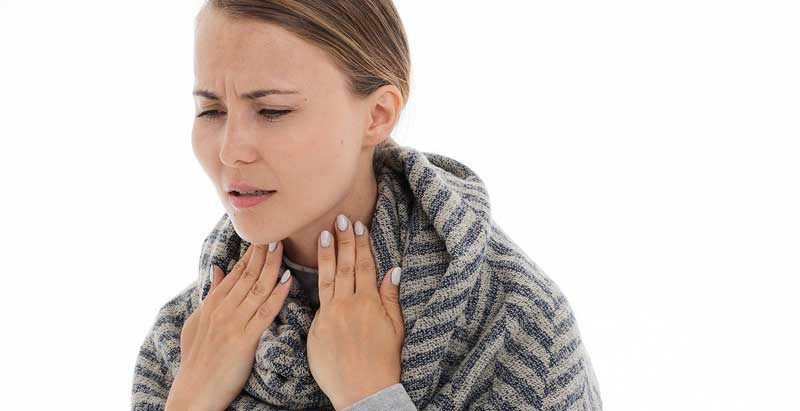 Eine Frau, die sich auf ihren schmerzenden Hals greift, Stichwort Corona. (c) Pixabay.com