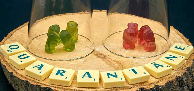 Drei grüne und drei rote Gummibären unter einem Glas, darunter steht mit Scrabble-Steinen das Wort Quarantäne. (c) Pixabay.com