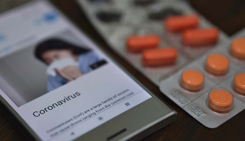 Covid-19 Fakten-Check: Wegweiser durch den 'Fake News Dschungel' 3 Ein Handy, auf dessen Screen sich eine Frau die Nase putzt und Coronavirus steht, daneben Tabeltten. (c) Pixabay.com