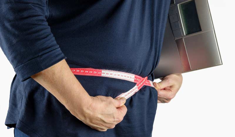 Migräne – wie "richtige" gesunde Ernährung zur Prophylaxe beiträgt 2 Ein Mann mit einer Körperwaage unter dem Arm, der seinen Bauchumfang misst. (c) Pixabay.com