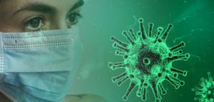 Das Gesicht einer Frau mit Mund-Nasenschutzmaske, daneben ein großes Coronavirus. (c) Pixabay.com