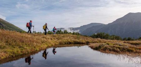 Wanderer in den Bergen, die sich in einem See spiegeln. (c) Naturfreunde/ Martin Edlinger