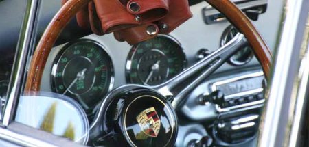 Das Lenkrad eines alten Porsches, auf dem Lederhandschuhe liegen. (c) Pixabay.com