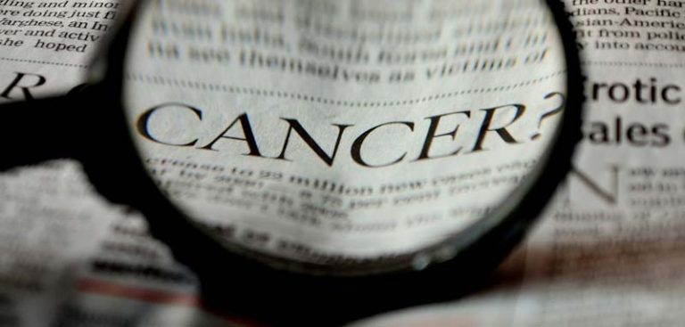 Eine Lupe über dem Wort "cancer" in einer Überschrift in einer Zeitung. (c) Pixabay.com