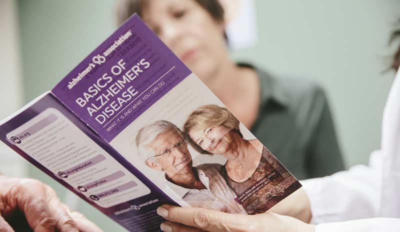 Zwei Frauen, die sich einen Folder "Basics of Alzheimer´s disease" anschauen, Stichwort Schutzimpfungen.
(c) Alz.org