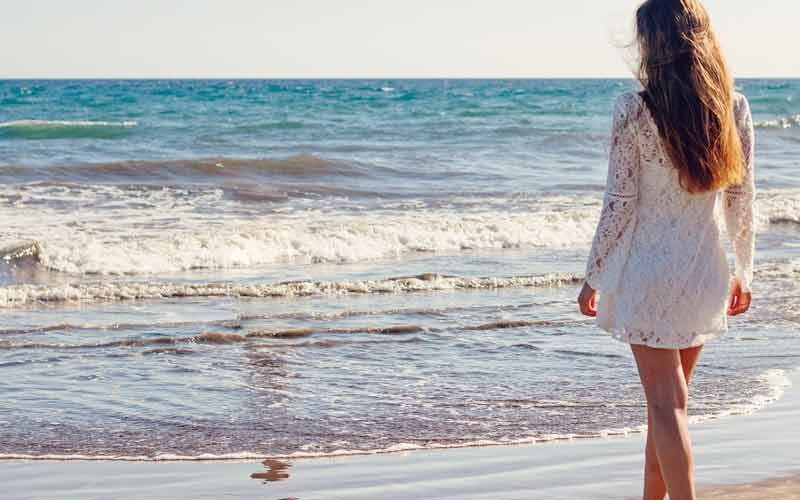 Eine Frau in ihrem Strandkleid am Strand mit Blick auf´s Meer, Stichwort Urlaubsfeeling.
(c) Pixabay.com