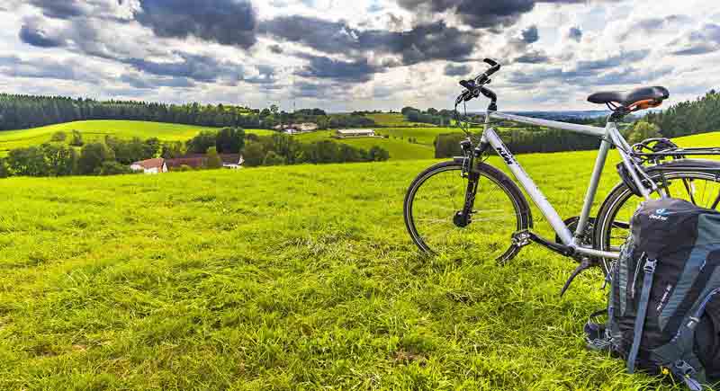 Ein Fahrrad auf einer Wiese, daneben ein Rucksack.
(c) Pixabay.com