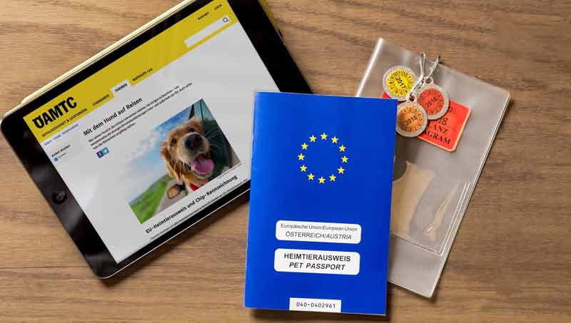 Ein Tablet mit einer offenen ÖAMTC-Seite, ein Heimtierausweis und Hundemarken, Stichwort mit Hund auf Urlaub.
(c) ÖAMTC