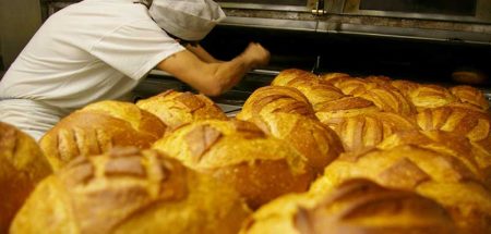 Brötchen, im Hintergrund ein Bäcker, der diese aus dem Backofen gibt. (c) Pixabay.com