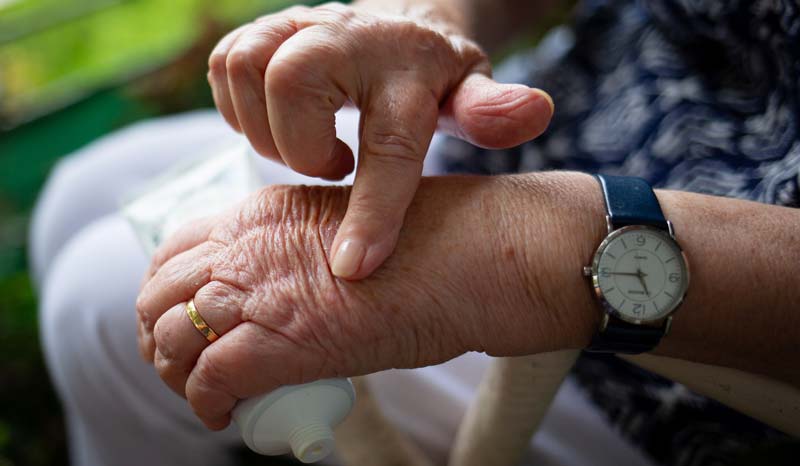 Die Hände einer alten Frau, die sich den Handrücken mit einer Salbe einschmiert, Stichwort Rheuma.
(c) Pixabay.com