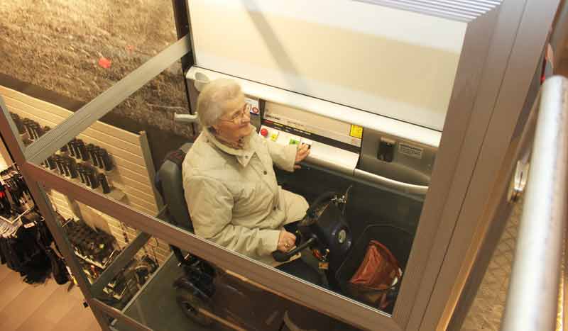 Eine Seniorin auf einem elektrischen Seniorenrollwagen in einem Aufzug, Stichwort das Leben leichter machen.
(c) Cibes Lift Group