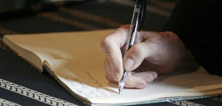 Eine Hand, die mit einem Kugelschreiber etwas in ein Buch schreibt. (c) Pixabay.com
