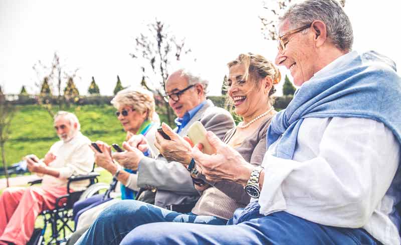 Erwartungen und Anforderungen der Smartphone-Nutzer 65+ 2 Senioren auf einer Bank im Freien, alle mit einem Smartphone in der Hand.
(c) Doro