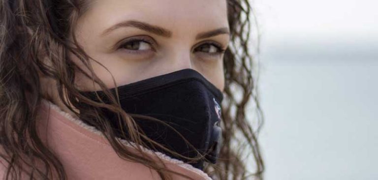 Der Kopf einer Frau, die über ihre Schulter zurück schaut und eine Mund-Nasen-Schutzmaske trägt. (c) Pixabay.com