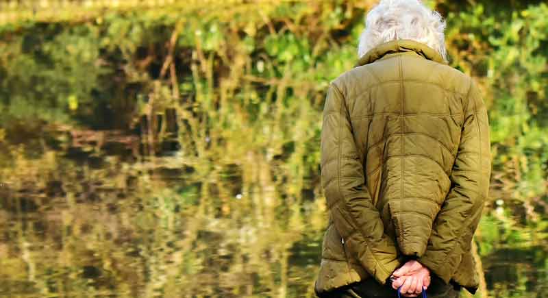 Eine alte Frau von hinten, die alleine vor einem See steht, Stichwort Tag der älteren Menschen.
(c) Pixabay.com