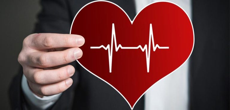 Eine männliche Hand, die ein rotes Herz mit weißen EKG-Linien vor sich hält. (c) Pixabay.com
