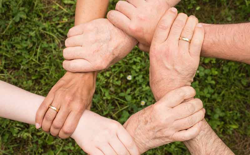 Die Hände von sechs Personen, die sich gegenseitig am Handgelenk haltend einen Kreis bilden.
(c) Pixabay.com