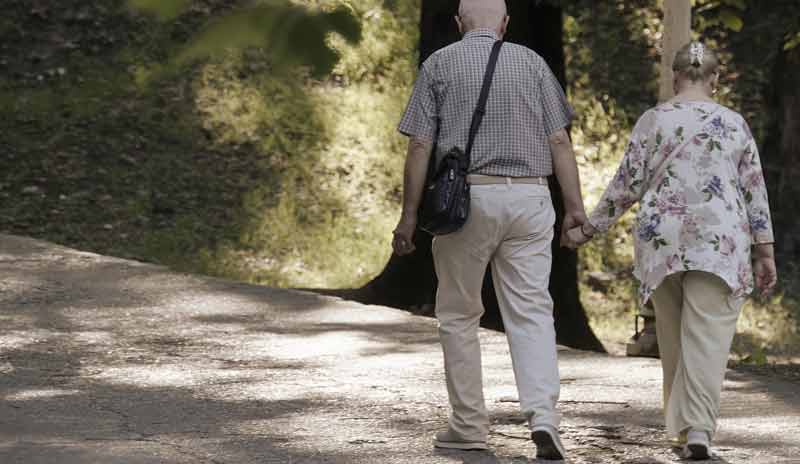 Eine alte Frau und ein alter Mann Hand in Hand beim Spazierengehen, Stichwort chronisch Kranke.
(c) Pixabay.com