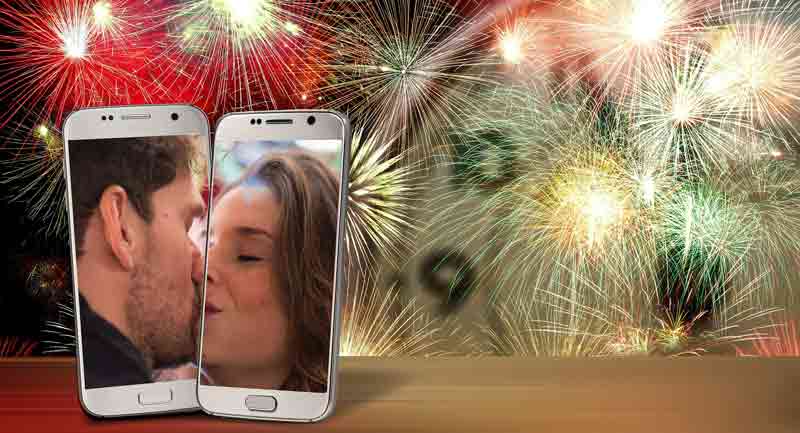 Im Hintergrund ein Silvesterfeuerwerk, davor zwei Smartphones, auf denen sich ein Mann und eine Frau küssen.
(c) Pixabay.com