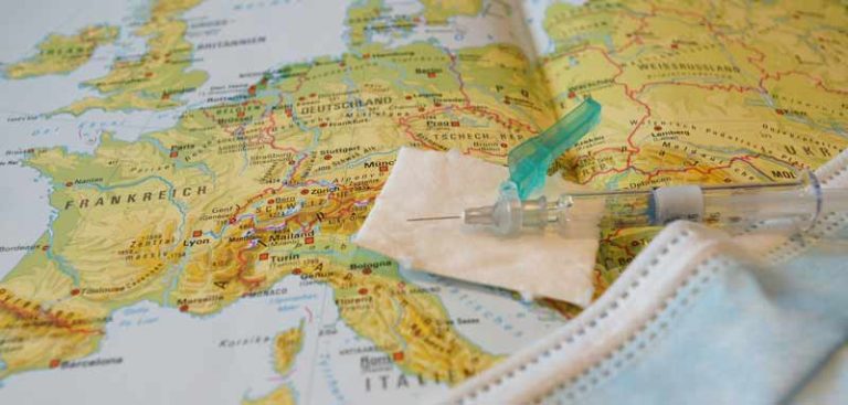 Eine Landkarte von Europa, auf der eine Spritze und ein Mund-Nasen-Schutz liegen. (c) Pixabay.com