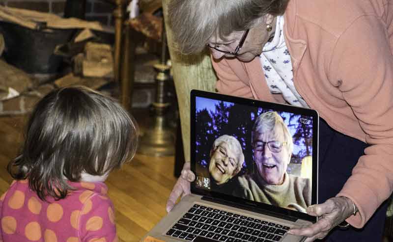 Eine ältere Frau, die ihrem Enkelkind einen Laptop mit einer Videokonferenz hält.
(c) Pixabay.com