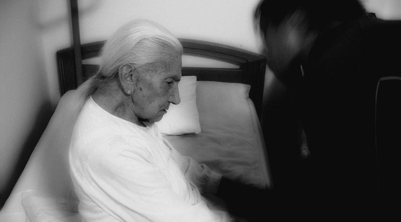 Eine alte Frau sitzt auf einem Bett, Stichwort Pflegende.
(c) Pixabay.com