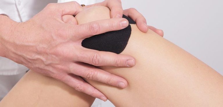 Die Hände eines Physiotherapeuten, der das Knie einer Frau taped. (c) Pixabay.com