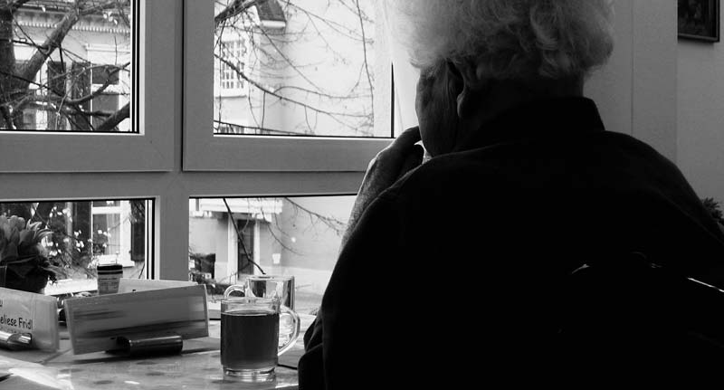 Eine alte Frau sitzt allein vor einem Fenster uns schaut hinaus, Stichwort Heimbesuche.
(c) Pixabay.com