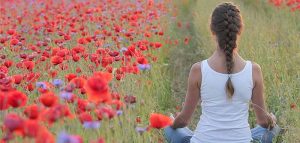 Psychische Entlastung: So kommen sie gesund durch die Pandemie Eine Frau beim Meditieren auf ein Feld mit blühendem Klatschmohn. (c) Pixabay.com