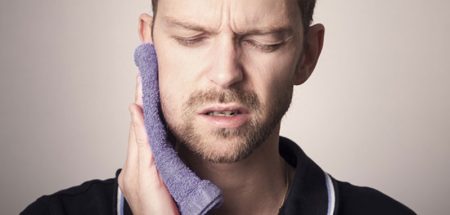 Das Gesicht eines Mannes, der sich seine Backe kühlt wegen Zahnschmerzen. (c) Pixabay.com