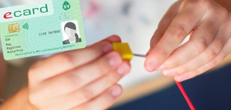 Die Hände einer Frau beim Durchfädeln einer Nadel durch einen kleinen Holzquader, darüber eine e-Card. (c) Ergotherapie Austria/ Schultz & Schultz