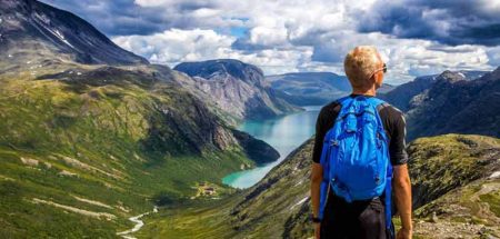 Ein Wanderer mit Rucksack vor einem Bergpanorama mit einem See im Hintergrund. (c) Pixabay.com