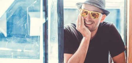 Ein lachender Mann mit Hut und Sonnenbrille schaut durch ein offenes Fenster. (c) Pixabay.com