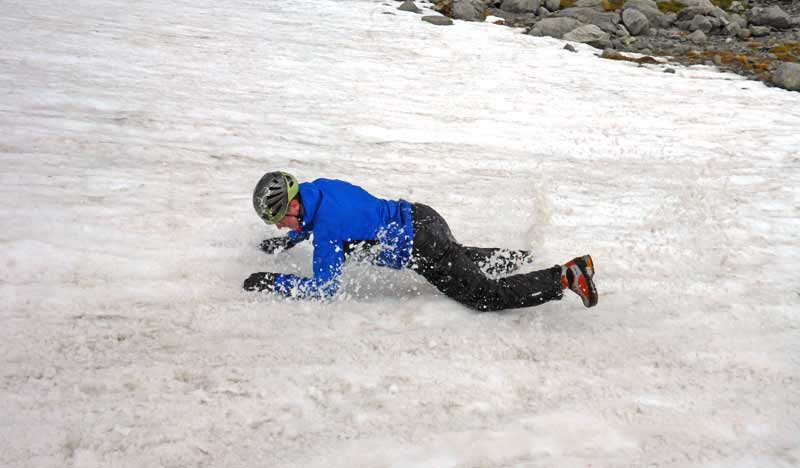 Ein Mann in Bauchlage, der auf einem Altschneefeld runter rutscht.
(c) Alpenverein/ Archiv