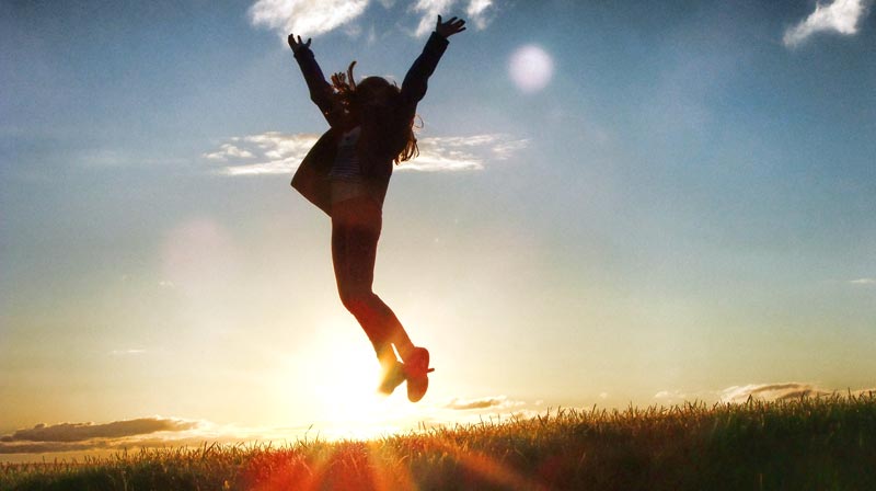 Die Silhouette einer vor Freude in die Höhe springenden Frau im Licht des Sonnenuntergangs, Stichwort Plan gegen die Corona-Kilos.
(c) Pixabay.com