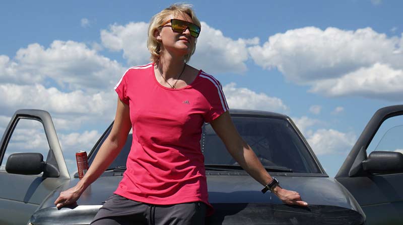 Eine Frau mit Sonnenbrille lehnt an der Motorhaube eines Autos, bei dem beide Türen offen sind.
(c) Pixabay.com