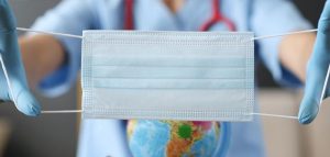 Covid-Pandemie: Dramatische Konsequenzen in Zukunft vermeiden Eine Mund-Nasen-Schutzmaske, die vor einem Globus gehalten wird. (c) Pixabay.com