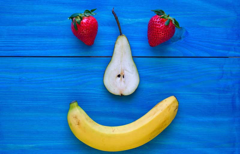 Ein Smiley aus zwei Erdbeeren als Augen, einer aufgeschnittenen Birne als Nase und einer Banane als lachenden Mund.
(c) Pixabay.com