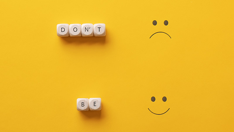 Ein trauriges Smiley, bei dem daneben mit Scrabble Würfeln Don´t steht. Und darunter ein lachendes, bei dem "Be" daneben steht, Stichwort Optimismus.
(c) AdobeStock