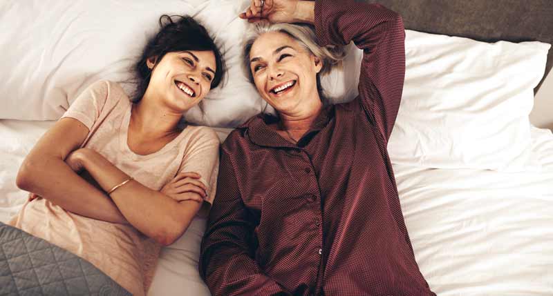 Zwei lachende Frauen auf einem Bett.
(c) AdobeStock