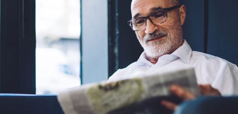 Ein älterer Mann mit Brille beim Zeitung Lesen. (c) AdobeStock