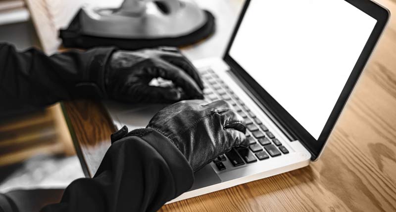 Jemand, der mit schwarzen Handschuhen auf einer Laptop-Tastatur tippt.
(c) AdobeStock