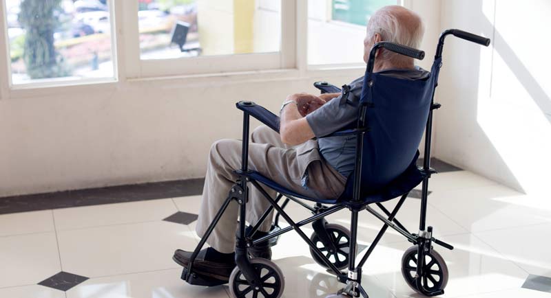 Ein alter Mann in einem Rollstuhl, der beim Fenster hinaus schaut.
(c) AdobeStock