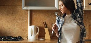 Was in den eigenen vier Wänden so abgeht, wenn keiner hinschaut Eine Frau, die mit einem Schöpflöffel als Mikrofon singt. (c) AdobeStock