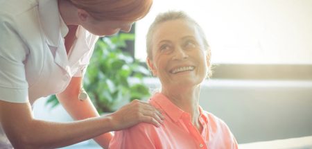 Eine Pflegerin, die mit einer Frau spricht, der sie die Hand auf die Schulter legt. (c) AdobeStock