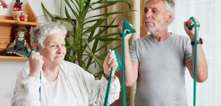 Ein Mann und eine Frau machen in einer Wohnung Übungen mit einem Gymnastikband. (c) Wiener Hilfswerk/ Nuderscher