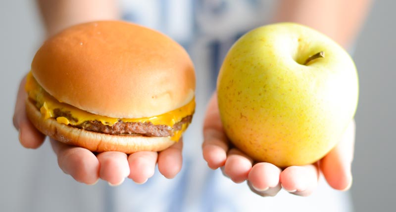 Famvital – gesunde Ernährung als ein ‘Schlüssel' für gesundes Altern 1 Die Hände einer Frau, die in einer Hand einen Burger und in der anderen einen Apfel hält.
(c) AdobeStock