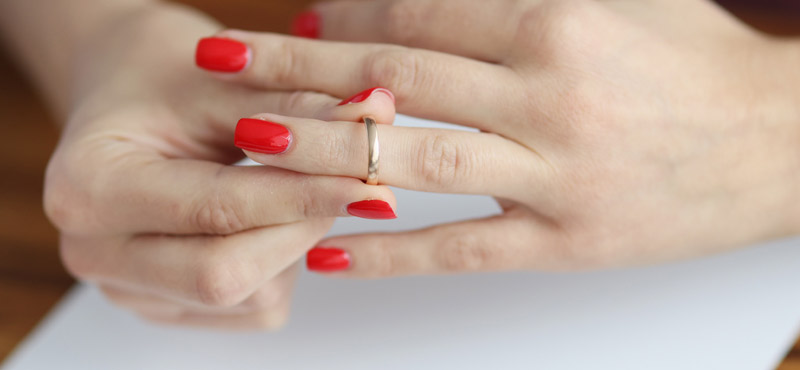Die Hände einer Frau, die ihren Ring vom Finger zieht, Stichwort Monogamie.
(c) AdobeStock