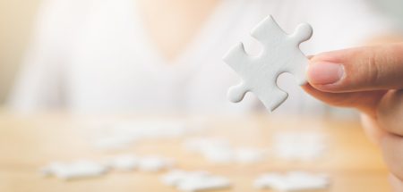 Die Finger einer Frau mit einem weißen Puzzleteil. (c) AdobeStock