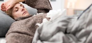 Gesund durch Herbst und Winter: auch auf Influenza vorbereiten Eine kranke Frau, die sich im Bett liegend die Hand an die Stirn hält. (c) AdobeStock